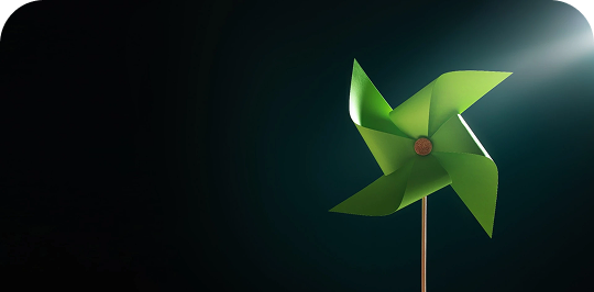 Molinillo de viento de papel verde sobre un fondo oscuro iluminado, que simboliza la energía eólica y limpia.