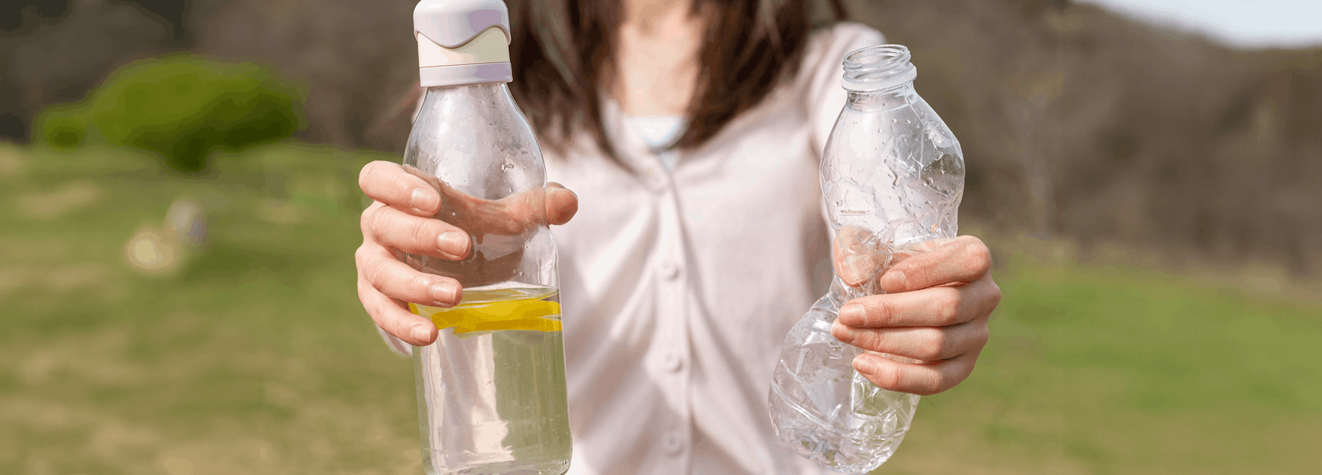 Mujer sostiene en su mano derecha un botilito de agua y en su mano izquierda una botella de plástico de un solo uso