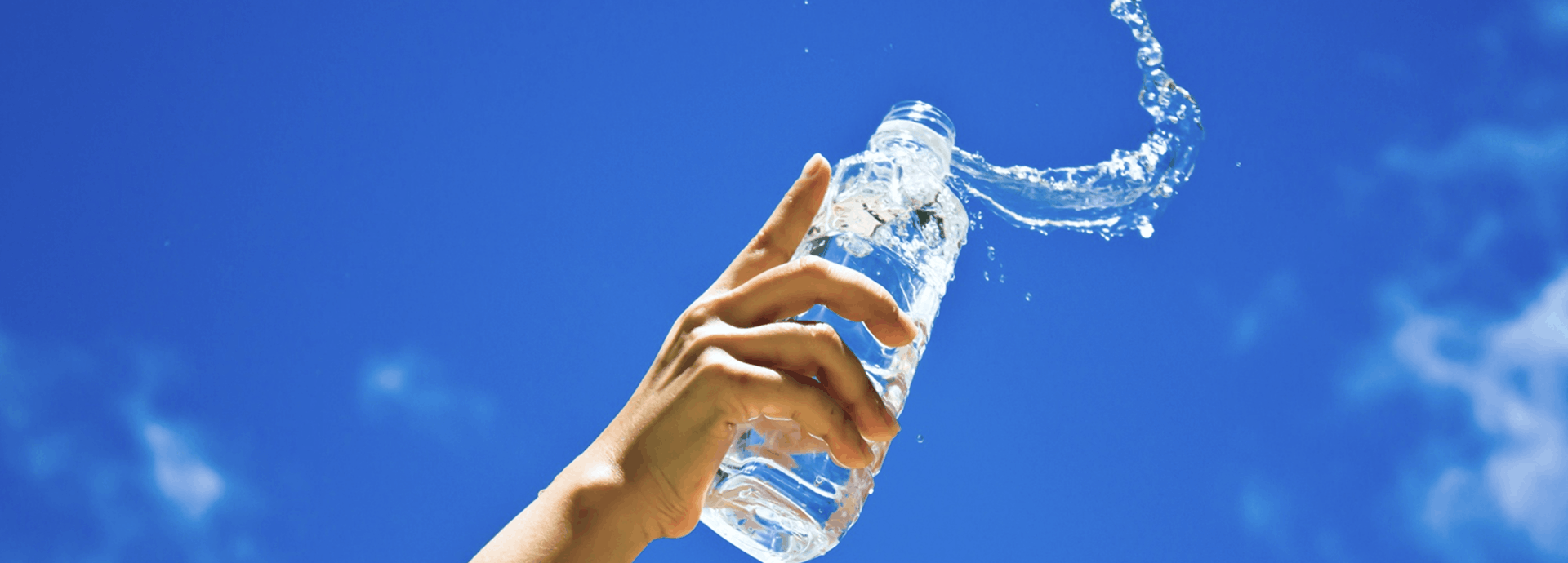 Mano derramando botella con agua en un lugar exterior
